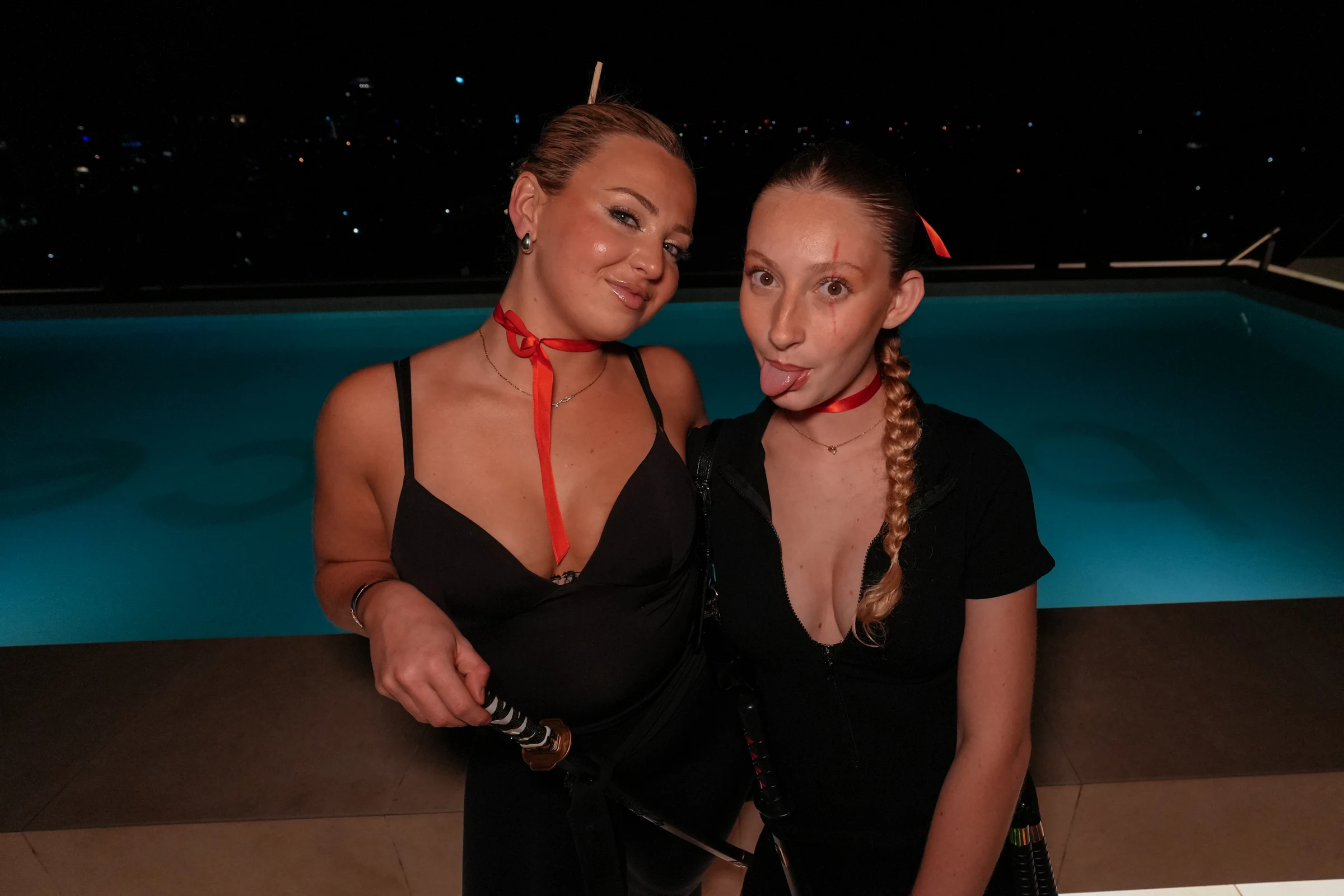 Two Halloween guests with red costume accessories beside the pool